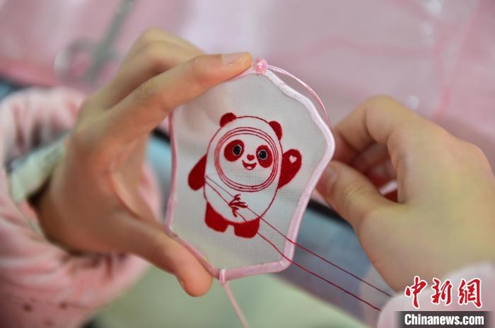 圖為一名小學生正在繡制2022年北京冬奧會吉祥物“冰墩墩”形象?！∮髟屏?攝