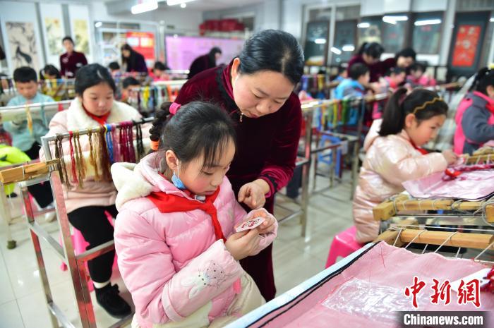 江西省級非遺豫章繡傳承人手把手指導小學生繡制2022年北京冬奧會吉祥物“冰墩墩”形象。　喻云亮 攝