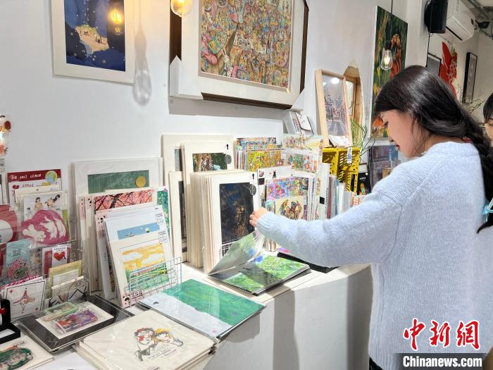 圖為藝術(shù)品商店內(nèi)，顧客挑選插畫作品。　鐘旖 攝
