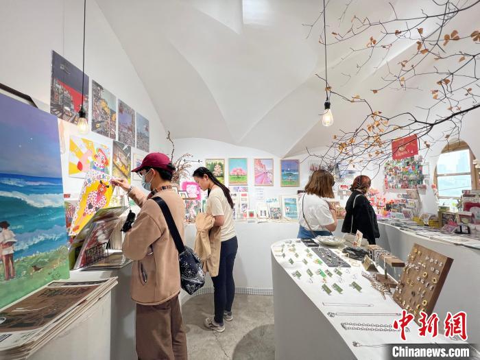 圖為藝術(shù)品商店內(nèi)，顧客挑選插畫作品?！＄婌?攝