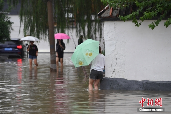7月31日，市民行走在雨中的北京房山區(qū)瓦窯頭村。北京市氣象臺(tái)當(dāng)日10時(shí)發(fā)布分區(qū)域暴雨紅色預(yù)警信號(hào)。北京市水文總站發(fā)布洪水紅色預(yù)警，預(yù)計(jì)當(dāng)日12時(shí)至14時(shí)，房山區(qū)大石河流域?qū)⒊霈F(xiàn)紅色預(yù)警標(biāo)準(zhǔn)洪水。<a target='_blank' href='/'><p  align=