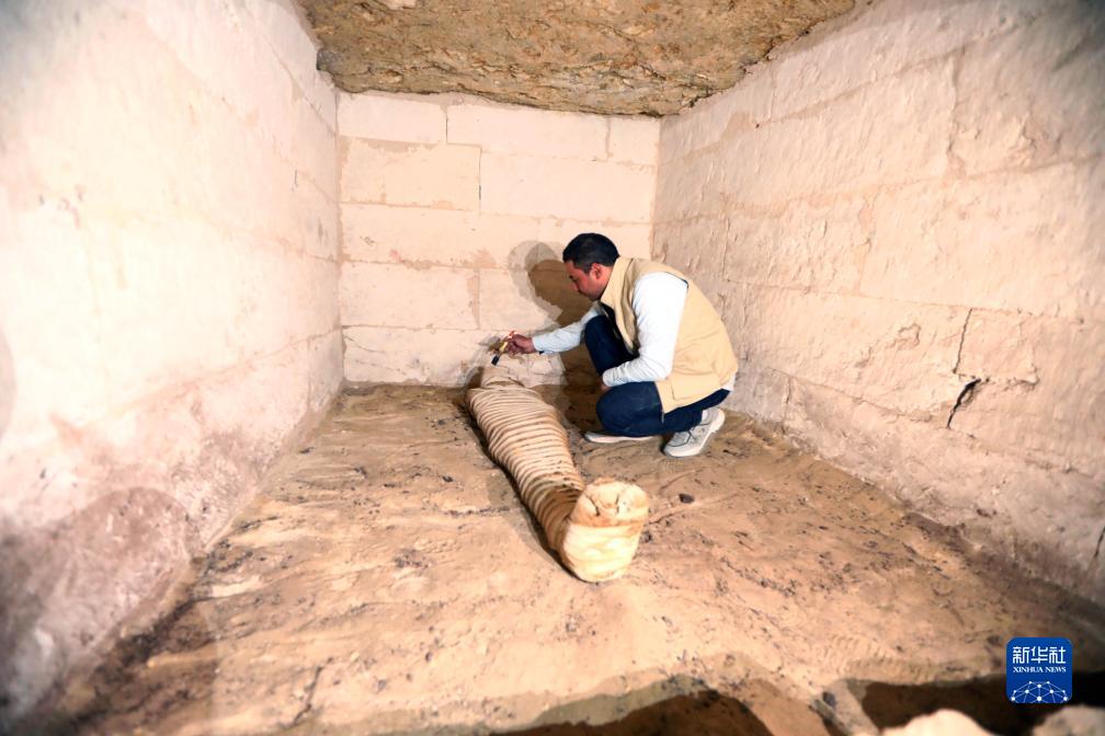 10月15日，在埃及明亞省考古現(xiàn)場(chǎng)，考古人員清理一座石鑿墓中的木乃伊。新華社發(fā)（艾哈邁德·戈馬攝）