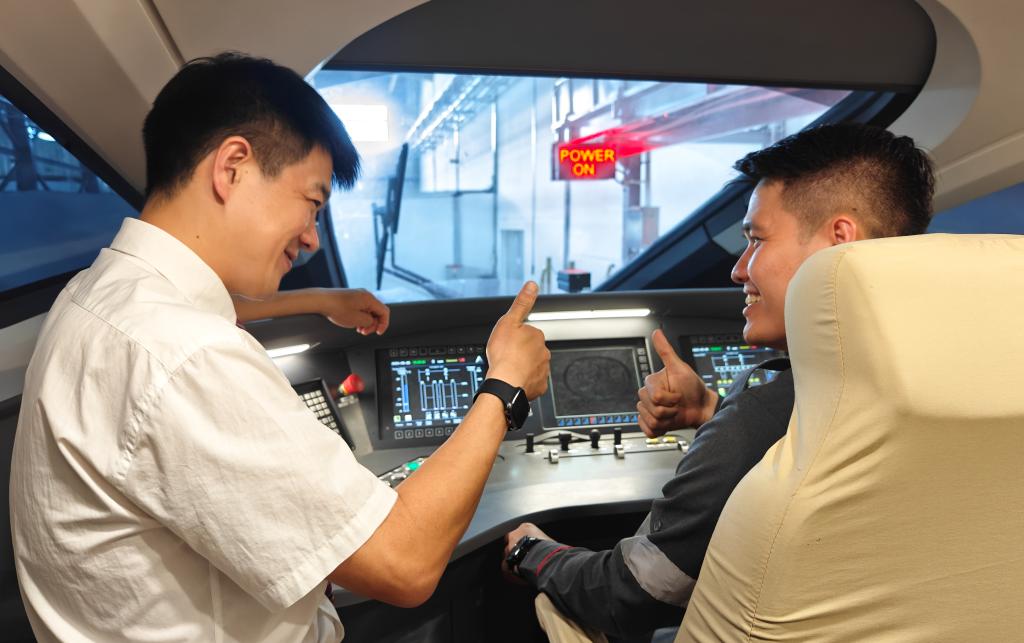 8月25日，在印度尼西亞萬隆的雅萬高鐵德卡魯爾動車所內(nèi)，中國師傅穆振（左）在向印尼火車司機(jī)塞蒂亞萬講解動車組出庫前的上電作業(yè)。