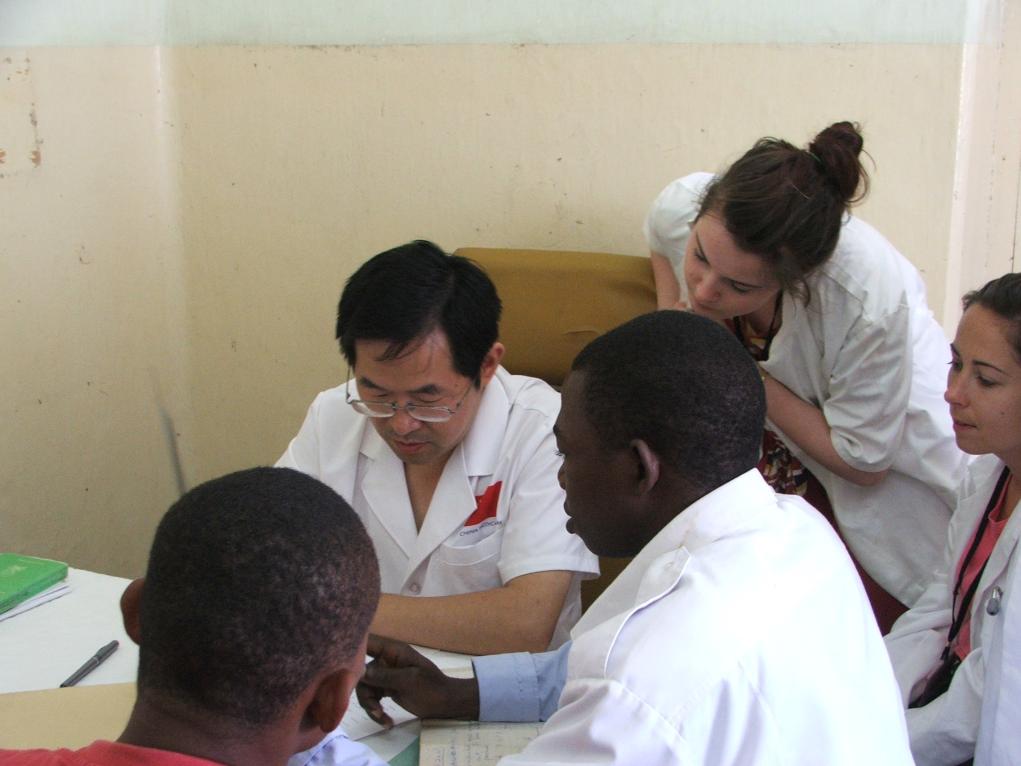 2011年7月22日，在坦桑尼亞桑給巴爾納茲莫加醫(yī)院外科門診，中國(guó)第24批援桑給巴爾醫(yī)療隊(duì)隊(duì)長(zhǎng)盧建林為當(dāng)?shù)鼗颊咴\治并帶教實(shí)習(xí)生。新華社發(fā)（國(guó)家衛(wèi)生健康委供圖）