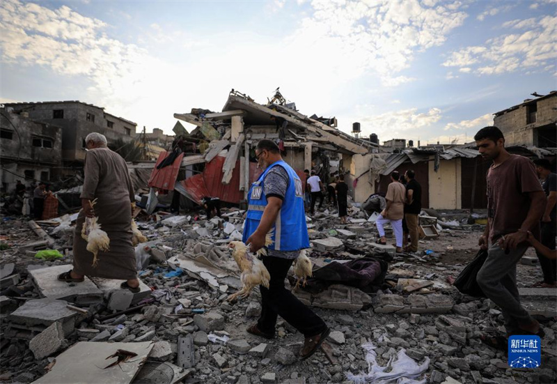 10月27日，在加沙地帶南部城市汗尤尼斯，人們經(jīng)過以軍襲擊后的房屋廢墟。