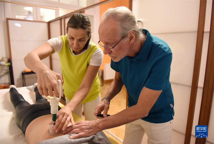 12月12日，在奧地利維也納，科格勒醫(yī)生（右）和助手在為病人進行拔罐治療。新華社記者 賀燦鈴 攝