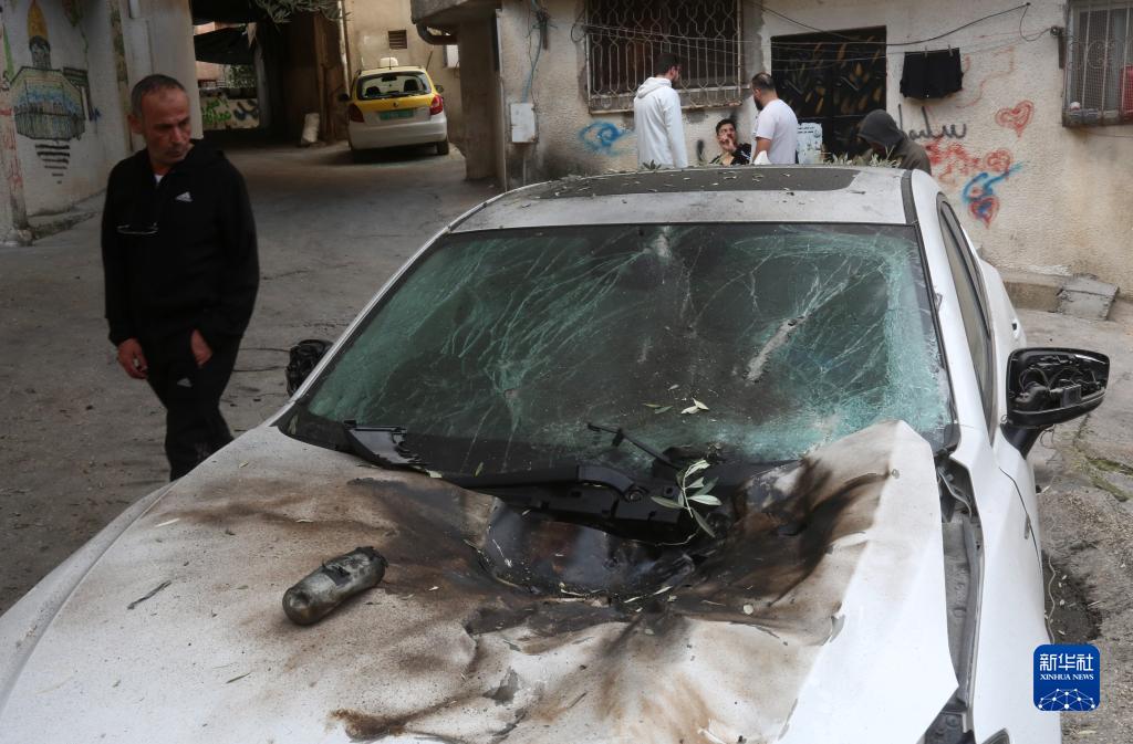 12月17日，在約旦河西岸城市圖勒凱爾姆附近的一處難民營，人們查看在沖突中損毀的車輛。新華社發(fā)（尼達(dá)爾·艾仕塔耶?dāng)z）