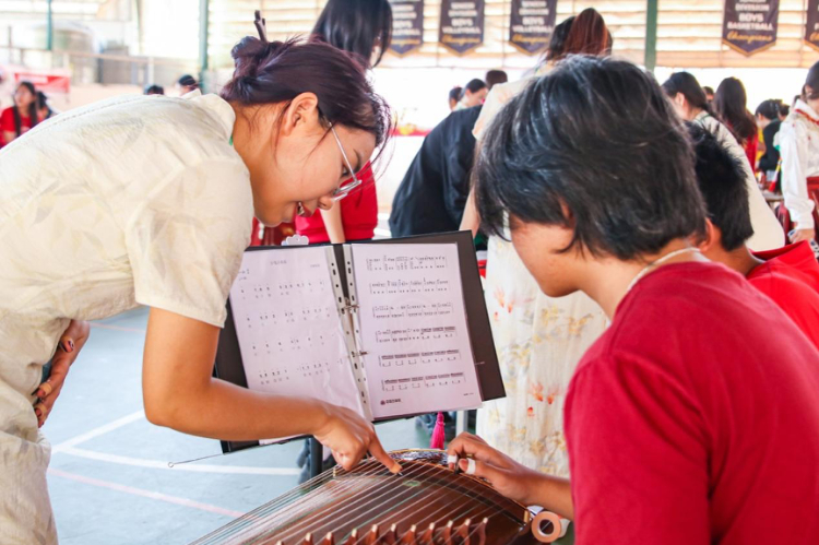 志愿者教師指導(dǎo)學(xué)生彈奏古箏?；顒又鬓k方供圖