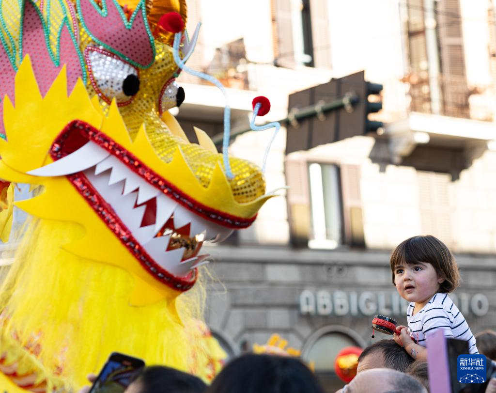 2月18日，在意大利羅馬，一名小朋友在彩妝巡游上觀看舞龍。新華社記者 李京 攝