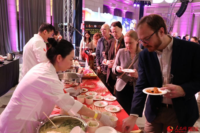 當(dāng)?shù)貢r(shí)間3月7日晚，華盛頓聯(lián)合車站廣場(chǎng)舉行駐美使團(tuán)“使館主廚挑戰(zhàn)賽”。圖為當(dāng)?shù)孛癖娫谥袊?guó)展臺(tái)前體驗(yàn)中國(guó)美食。人民網(wǎng)記者 李志偉攝