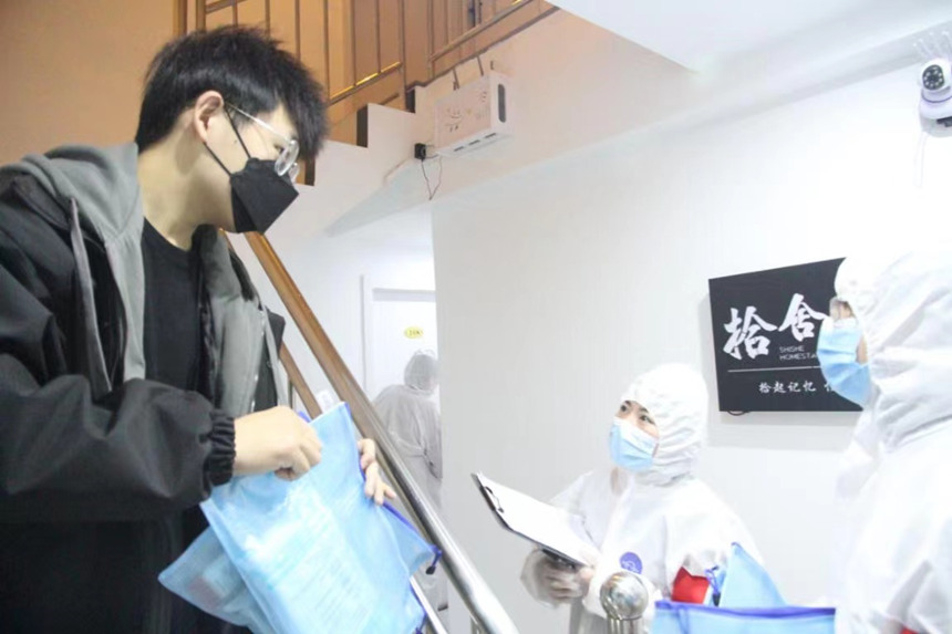 社區(qū)工作人員和志愿者身穿防護服上門送馬應龍大健康防疫包。徐帥攝