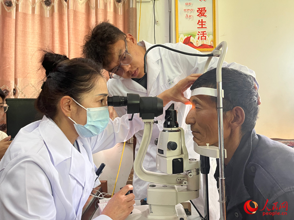 王紅英（左）和團(tuán)隊(duì)成員為達(dá)熱村村民檢查眼睛。人民網(wǎng)記者 杜燕飛攝