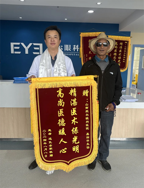 達(dá)瓦老人向吳四華（左）贈送錦旗。受訪者供圖