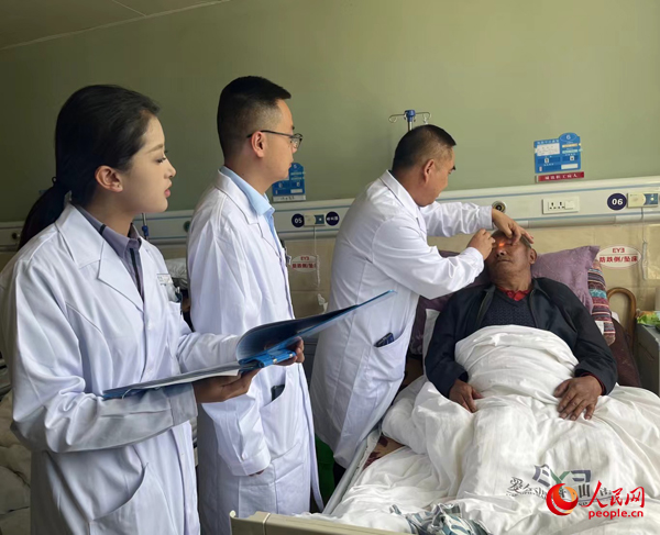 董光明（左三）帶領(lǐng)醫(yī)生對患者進(jìn)行術(shù)前檢查。人民網(wǎng)記者 杜燕飛攝