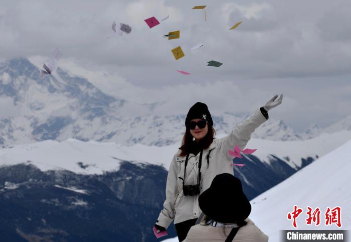 圖為5月14日，游客在西藏林芝色季拉山觀景臺拋灑“隆達”(風(fēng)馬旗，藏族民眾的一種祈福方式)?！±盍?攝
