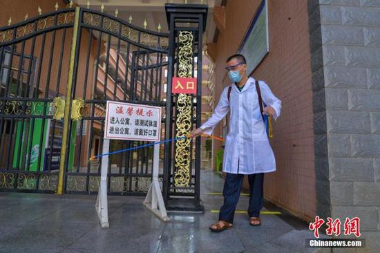 資料圖：海口經(jīng)濟(jì)學(xué)院的工作人員在學(xué)生宿舍樓入口消毒。 中新社記者 駱云飛 攝