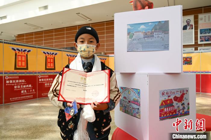 圖為一名獲獎學生與自己的繪畫作品合影?！≮w朗 攝