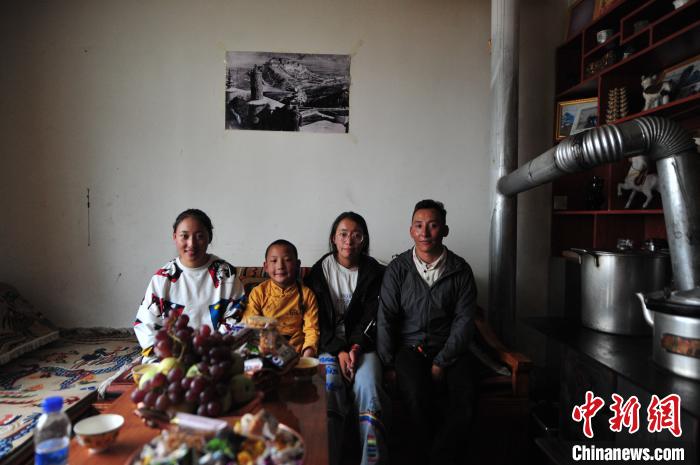 圖為8月12日，2018年7月從距那曲市色尼區(qū)城區(qū)那曲鎮(zhèn)90千米外的古露鎮(zhèn)當(dāng)桑村搬遷至城區(qū)的旦增(右一)與家人在80多平方米的新家合影(資料圖)。　張偉 攝