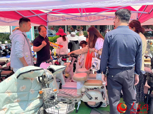 某電動(dòng)自行車品牌工作人員向消費(fèi)者介紹以舊換新相關(guān)情況。人民網(wǎng)記者 杜燕飛攝