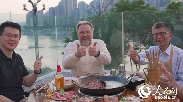 康寧顯示科技事業(yè)部全球拓建項(xiàng)目總監(jiān)軻寶華（中）和同事在重慶南濱路吃火鍋。人民網(wǎng)記者 蘇纓翔攝