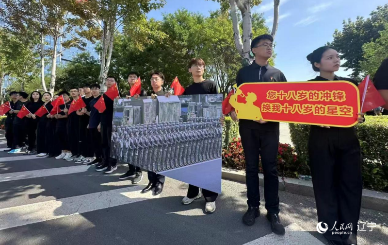 沈陽市人民廣場上，大學(xué)生們手持閱兵的圖片，告慰英烈。人民網(wǎng)記者 周頌雪攝