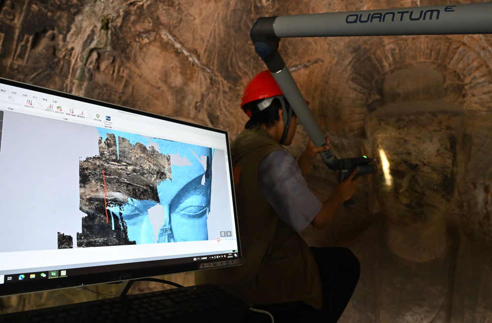 2025年4月9日，武漢大學(xué)文化遺產(chǎn)智能計算實驗室團隊成員在魏字洞使用關(guān)節(jié)臂掃描儀對佛像進行數(shù)字化掃描。圖片來源新華社