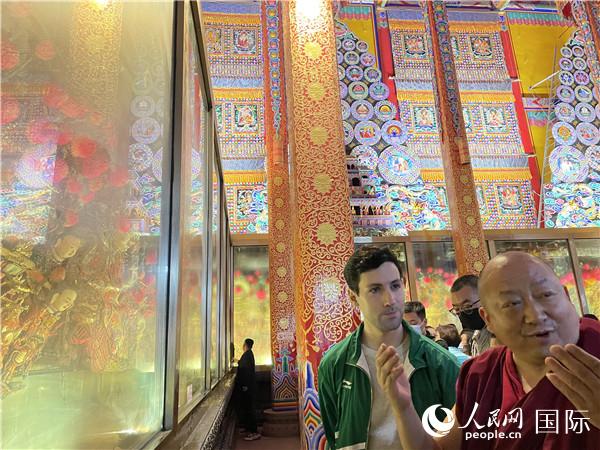 7月25日，省級(jí)非物質(zhì)文化遺產(chǎn)項(xiàng)目塔爾寺酥油花的代表性傳承人朋措堅(jiān)參（右）在塔爾寺酥油花館講解酥油花的制作過程。人民網(wǎng) 謝瑩攝