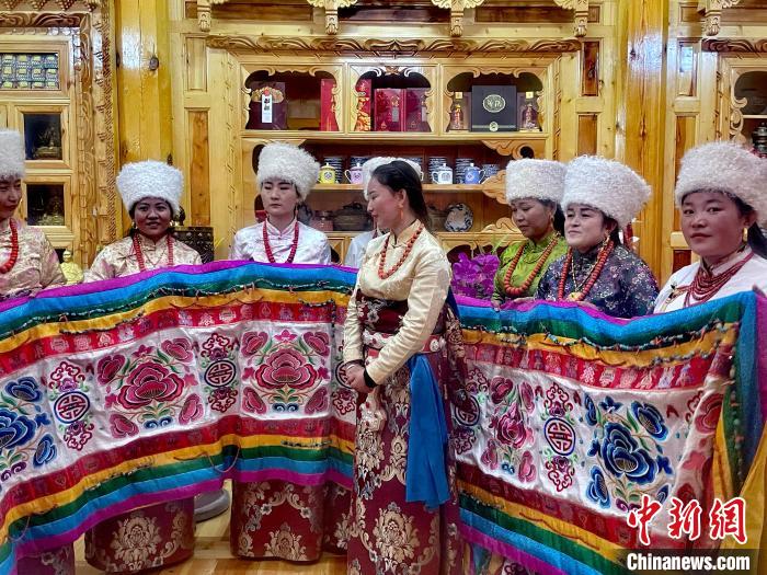 圖為女性展示村民自發(fā)繡制的“百米五彩哈達”?！±钣穹?攝