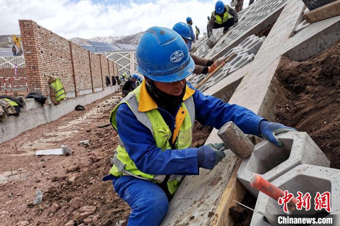 圖為光伏發(fā)電項目施工區(qū)工人在護(hù)坡鋪設(shè)空心磚?！±铍h 攝