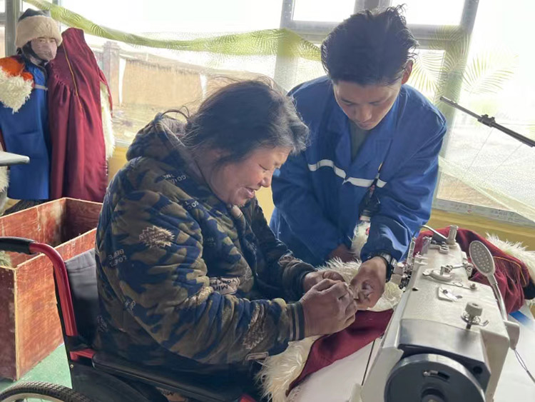 扎西奪爾登幫助殘疾員工裁剪。阿壩州文明辦供圖