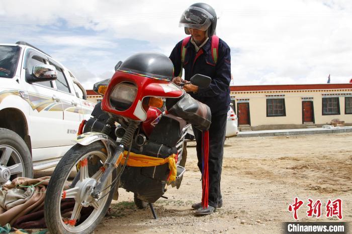 圖為白瑪準(zhǔn)備騎摩托車巡湖?！≮w朗 攝