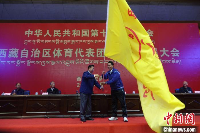 西藏自治區(qū)副主席甲熱·洛桑丹增授代表團團旗，西藏自治區(qū)體育局局長尼瑪次仁接旗?！∪轿木?攝