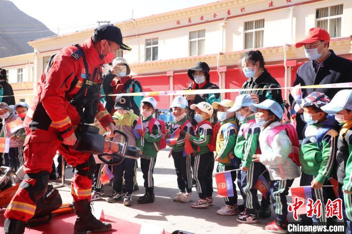 圖為消防指戰(zhàn)員為學(xué)生講解、演示先進救援裝備?！≮w琳 攝