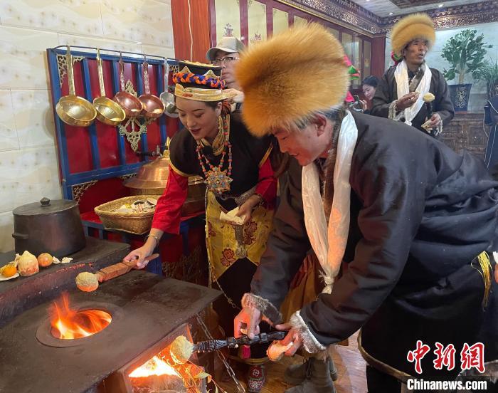 圖為人們在火上烤節(jié)日美食“結(jié)達”。　冉文娟 攝