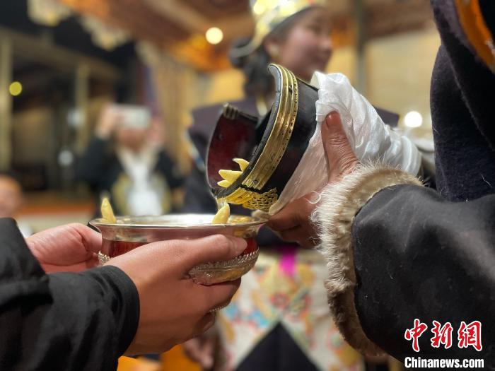 圖為主人在碗中斟滿青稞酒?！∪轿木?攝