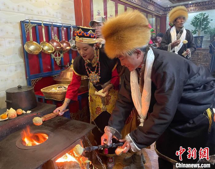 圖為人們在火上烤節(jié)日美食“結達”?！∪轿木?攝