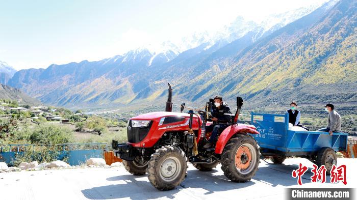 圖為工作人員將把加工完成的糌粑運送至村民手中?！〖卫杩h融媒體中心供圖