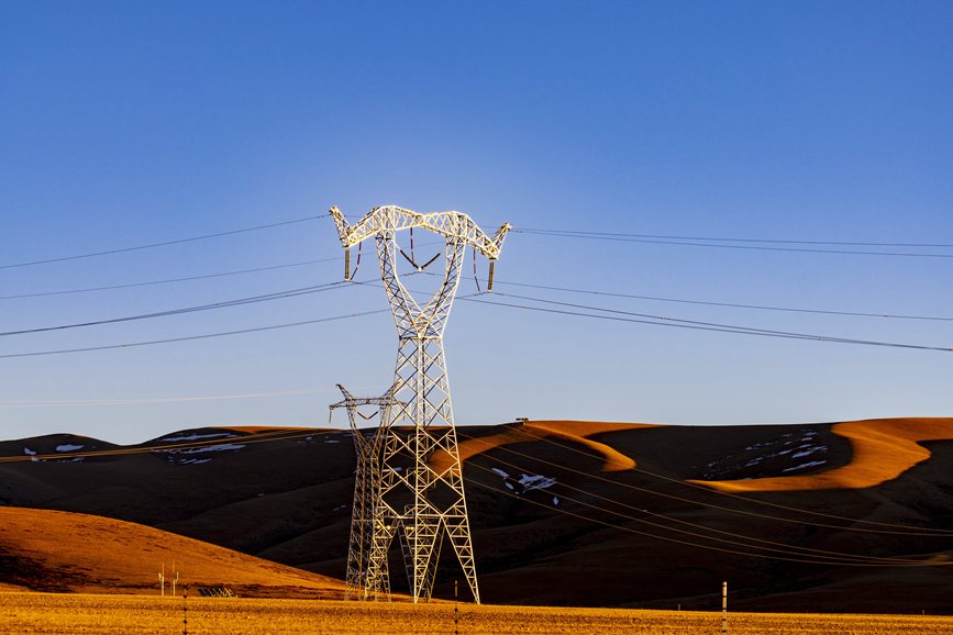 阿里地區(qū)的曠野上，電力鐵塔在夕陽下熠熠生輝。