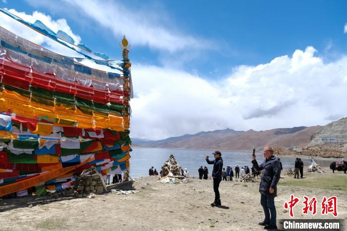 進(jìn)藏參訪嘉賓在羊湖畔拍攝經(jīng)幡?！〗w波 攝