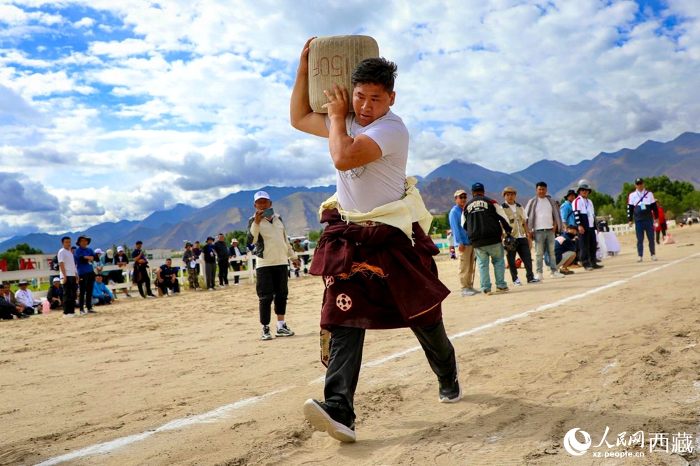 來(lái)自拉薩市當(dāng)雄縣的牧民選手將一塊150斤重的石頭扛在肩上飛奔。