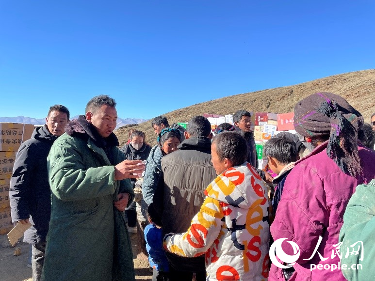 定日縣公安局干警頓珠次仁（左二）正在協(xié)助分發(fā)物資。人民網(wǎng)記者 郝潔攝